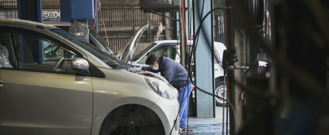 Mechanik naprawia srebrny samochód