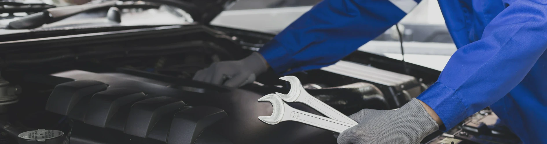 Mechanik w niebieskim stroju roboczym naprawiający samochód